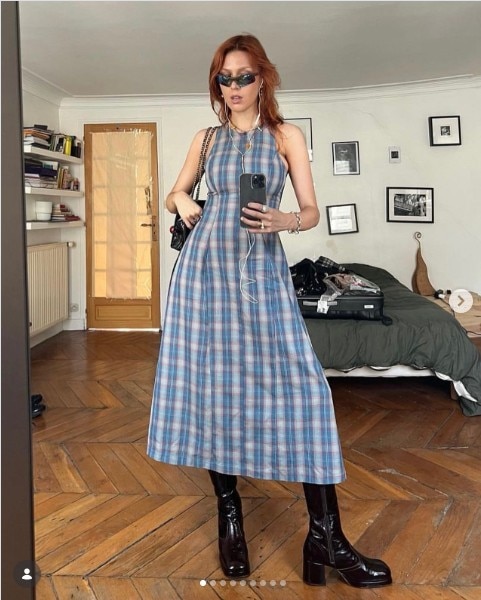 Young woman with red hair takes a photo in a mirror of herself wearing a sleeveless blue patterned dress.