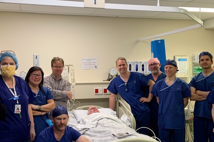 Doctors and nurses stand around a patient in a bed