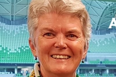 A woman smiles as she stand inside a room in a stadium