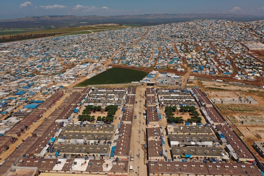 Tents, seen from an aerial view, stretch over the top of several hills.