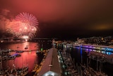 An aerial shots shows red fireworks over the water in Hobart