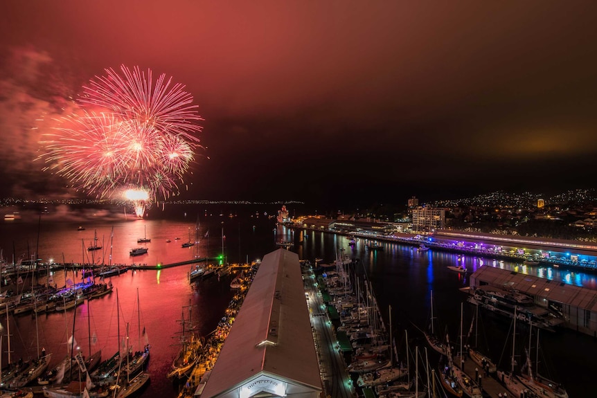 An aerial shots shows red fireworks over the water in Hobart