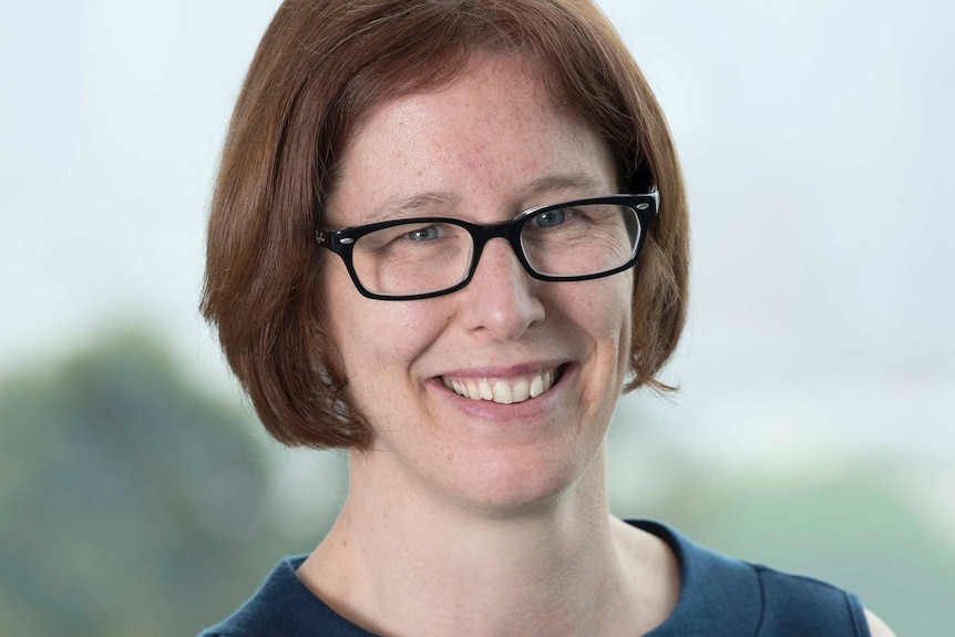 A headshot of a woman wearing glasses and blue top.