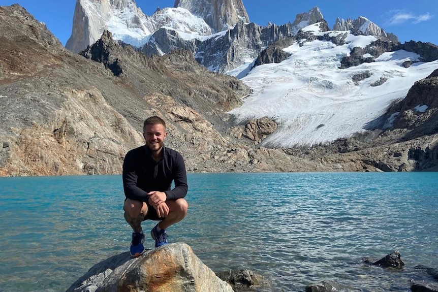 A man poses near a mountain lake.