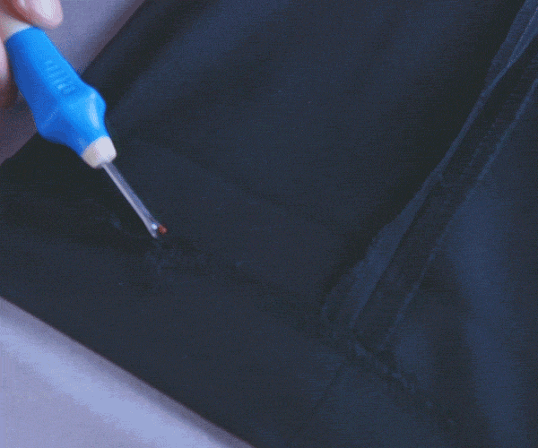 Gif of a hand using the quick unpick to remove the original hem.
