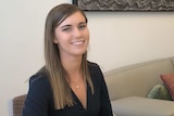 Woman sitting at a desk, smiles for the camera.