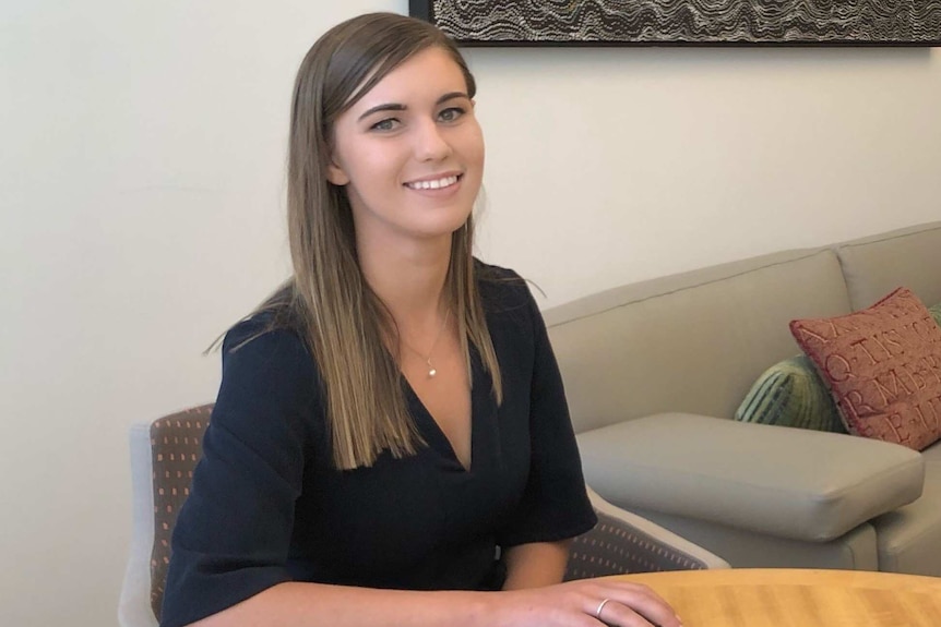 Woman sitting at a desk, smiles for the camera.