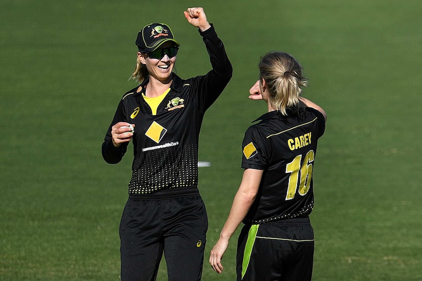 Two Australian female T20 cricketers congratulate each other following the dismissal of a New Zealand batter.