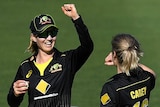 Two Australian female T20 cricketers congratulate each other following the dismissal of a New Zealand batter.