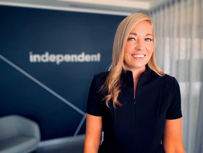Grace Hooper smiles in front of a sign that says 'Independent'.