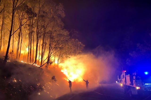 Firefighters try to extinguish a blaze burning along a roadside cliff at cunningham's gap.