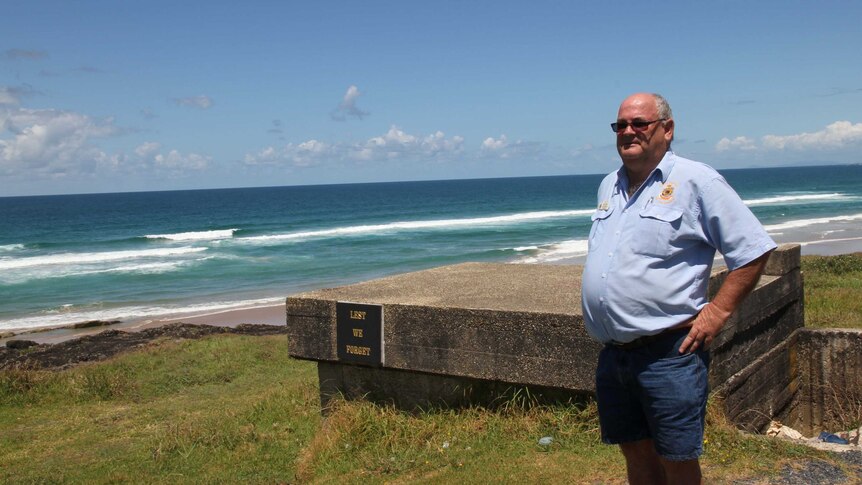 Bob Payne standing next to a concrete structure on a hill with the ocean in the background