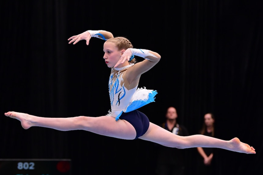 Jamie Wilson jumps to do the splits while doing a floor routine.