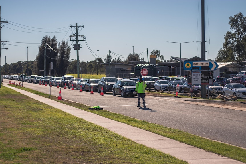 Long queues of cars with a man in a a neon green vest in the foreground