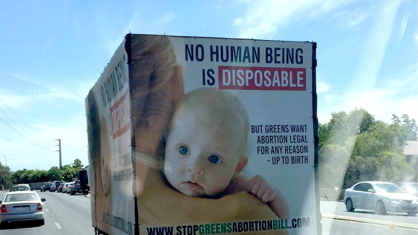 A mobile billboard on a truck with a picture of a baby saying no human being is disposable.