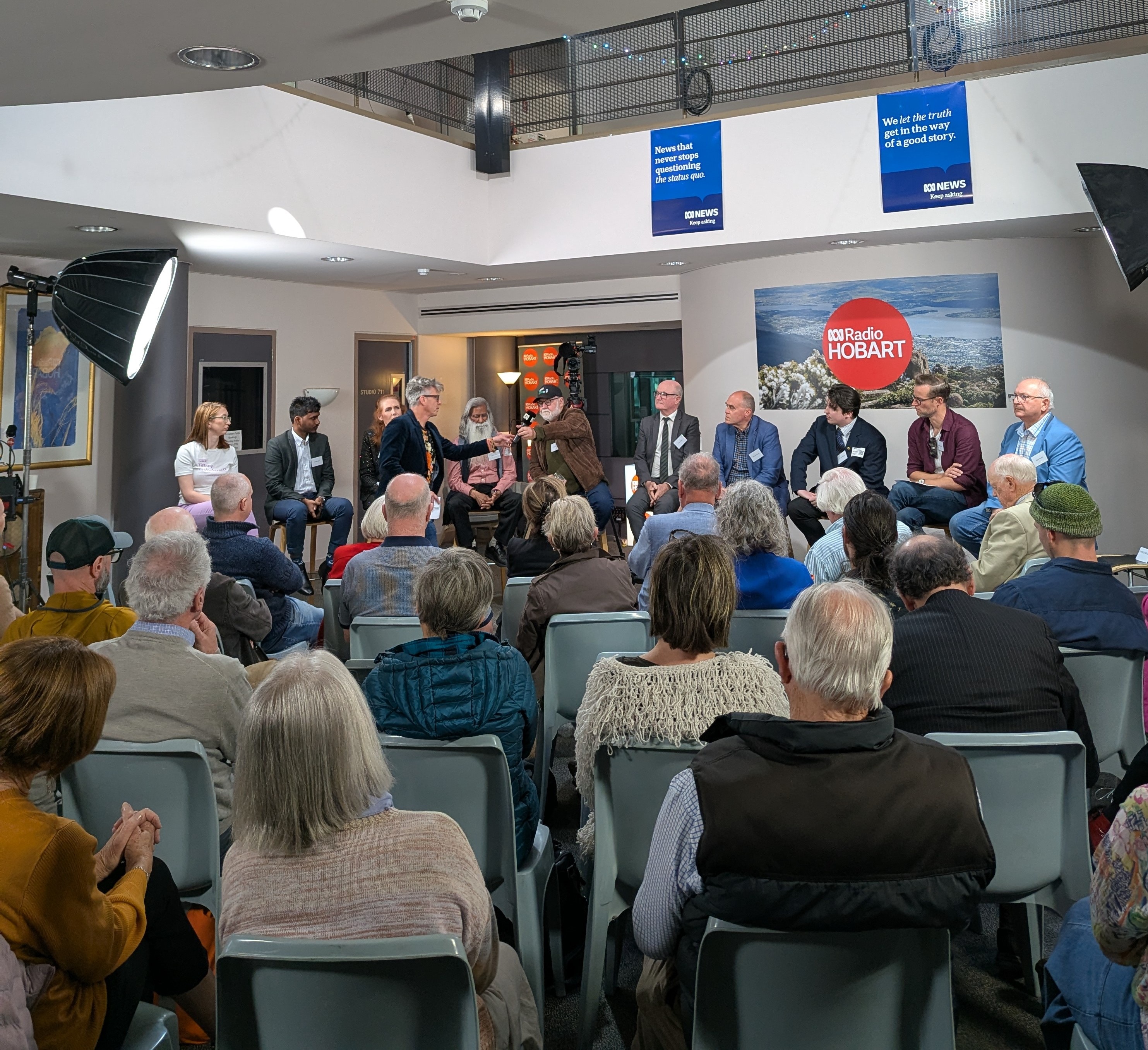 a group of people sitting in chairs watching 10 people on stools at a forum