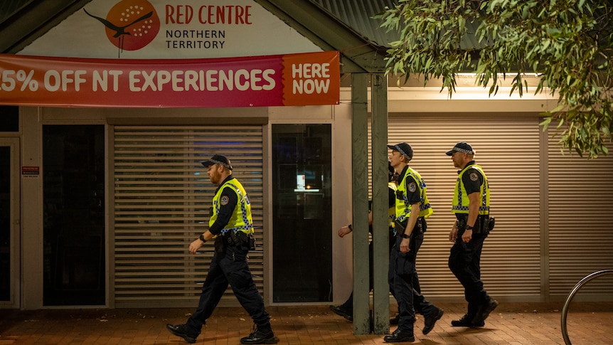 Police walk along a street at night.