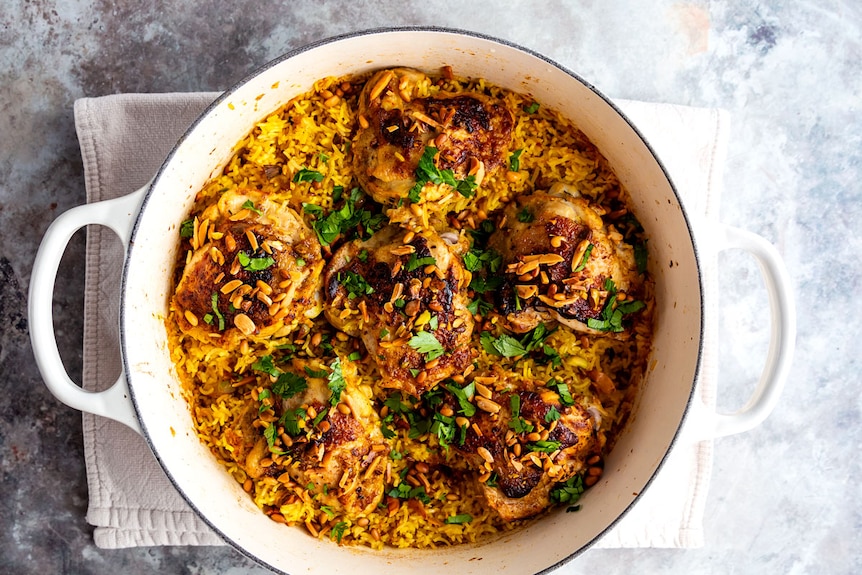 Saffron chicken and rice bakes in one pan and is served with toasted nuts and parsley, an easy dinner.