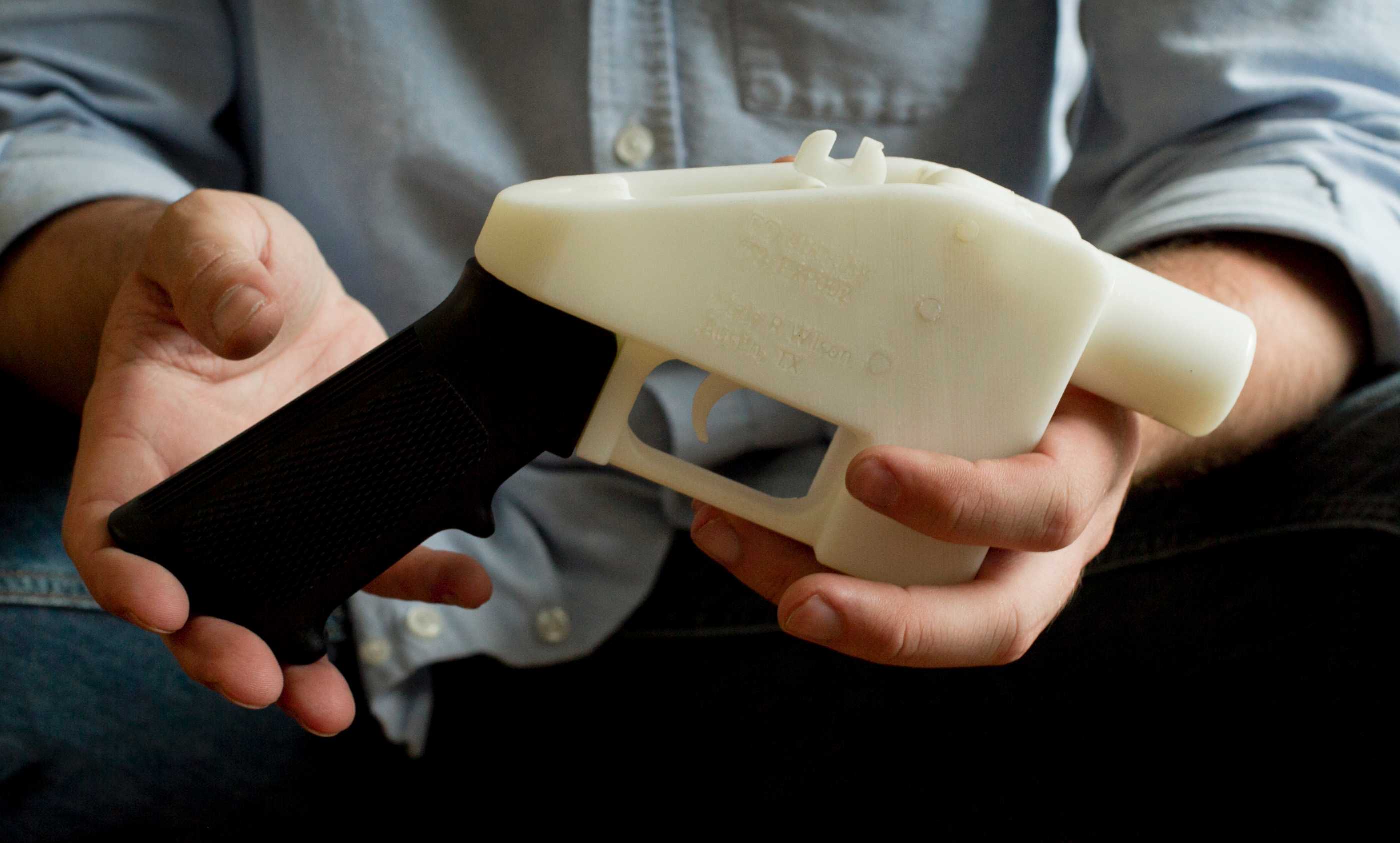 Man holds black and white 3D printed pistol