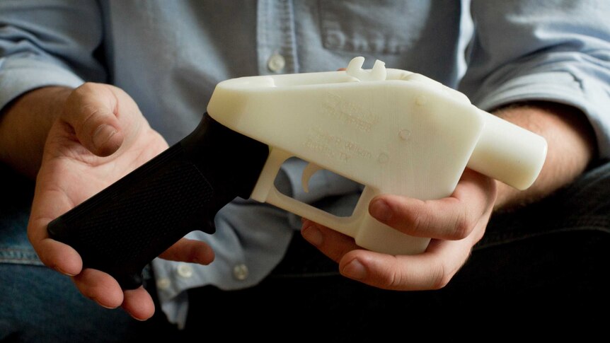 Man holds black and white 3D printed pistol