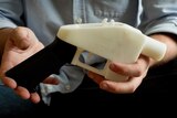 Man holds black and white 3D printed pistol