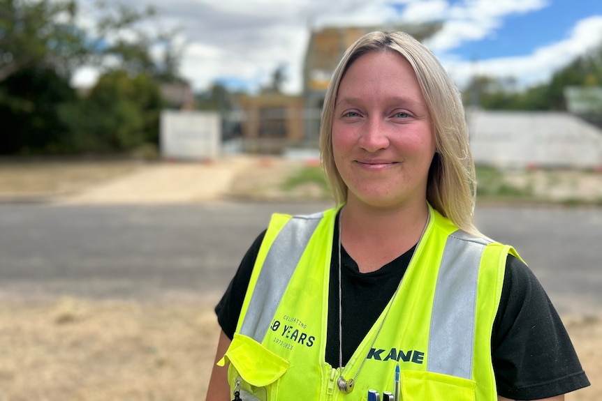 A woman wearing a hi viz jacket standing in front of a construction site