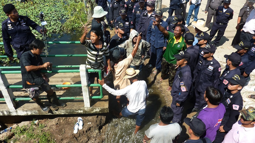 Bangkok residents argue with police as they gather to demand the wider opening of a sluice gate in Bangkok