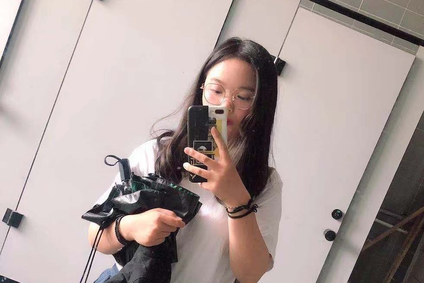 A Chinese woman is taking selfie in a change room.