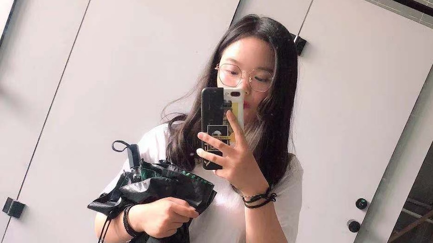 A Chinese woman is taking selfie in a change room.