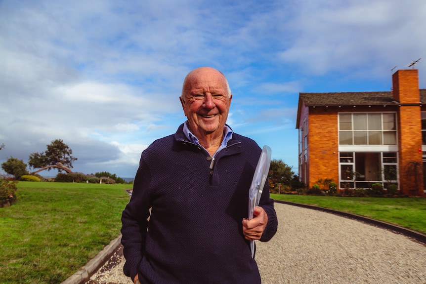 Beaumaris resident Neville Fuller smiles on a sunny day in front of a brick home.