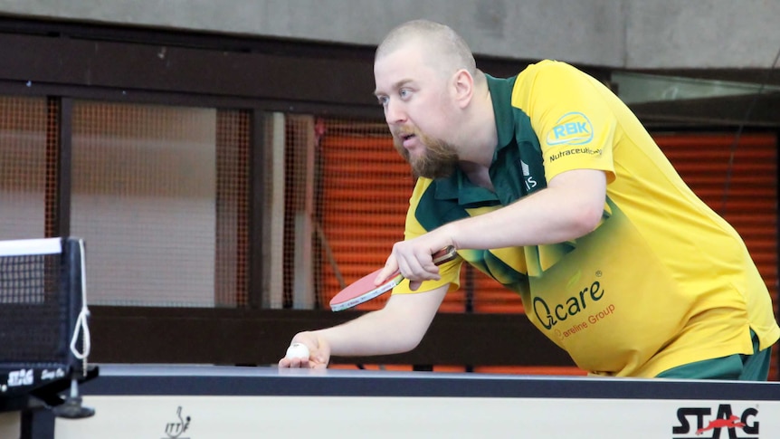 Trevor prepares to serve during a table tennis match.