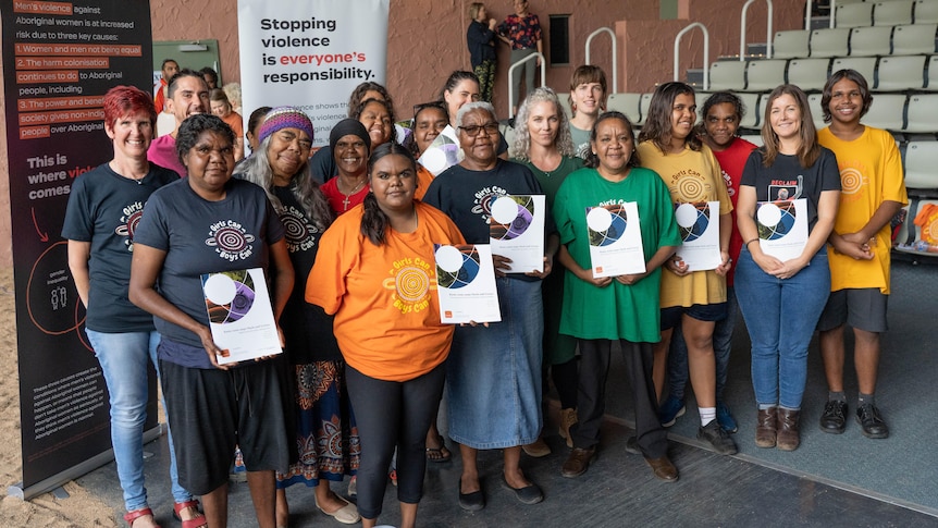 A group of mainly Indigenous women smiling, with some holding reports in their hands