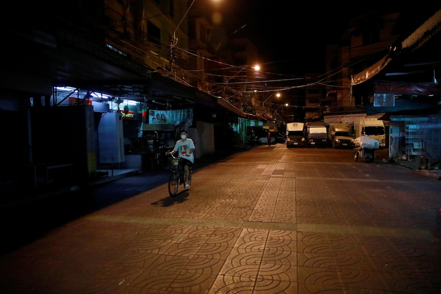 A man on a bike is the only person on a Bangkok street. 
