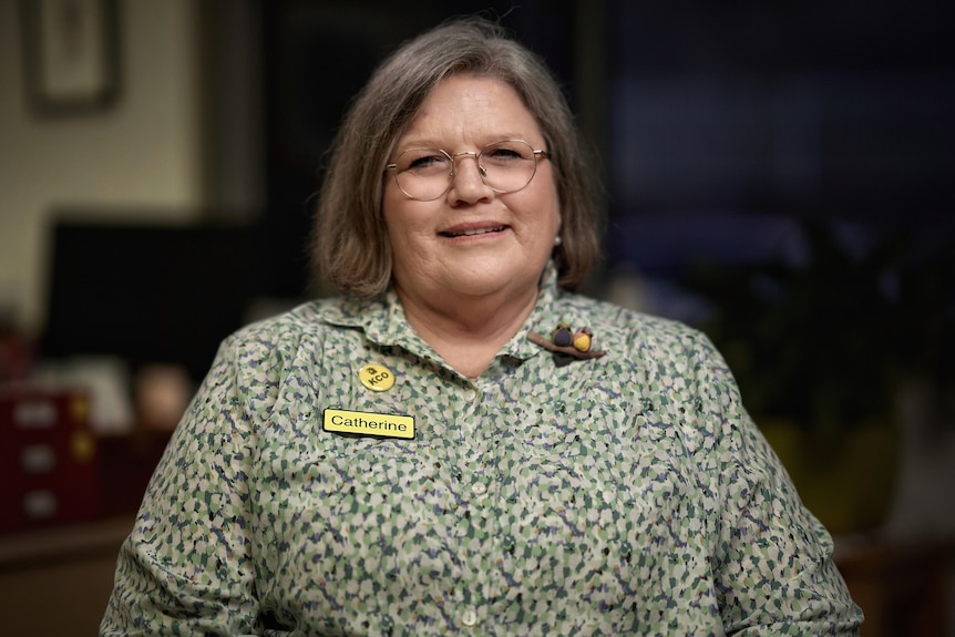 Woman wearing a green printed shirt with a name badge.