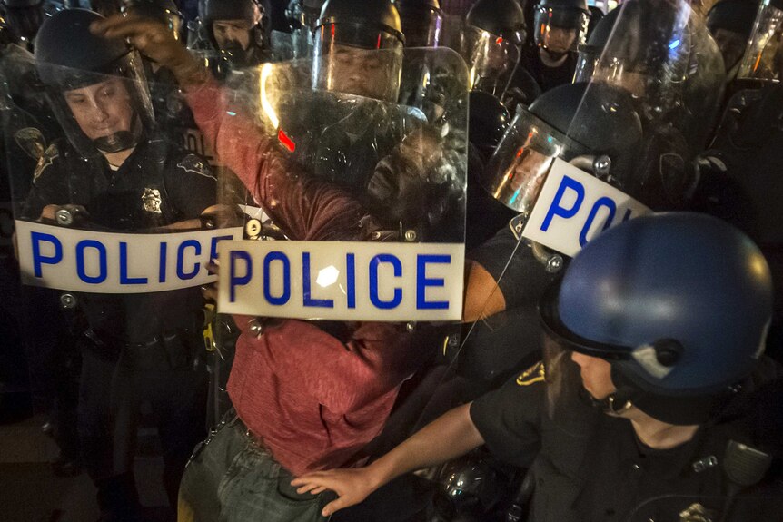 A protestor in Baltimore is detained by police after defying a curfew