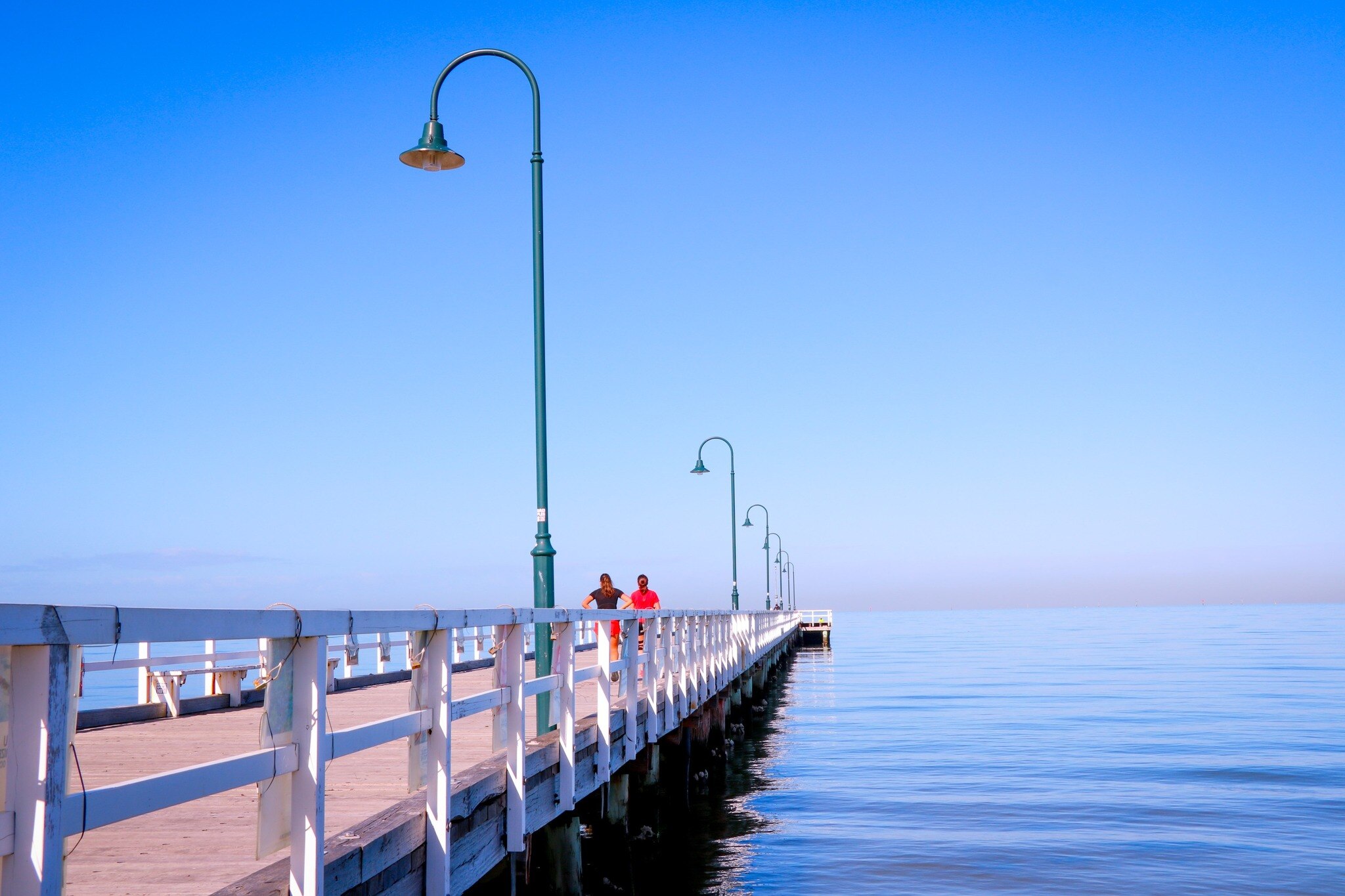 two people walk along the Kerferd Road Pier, Albert Park 