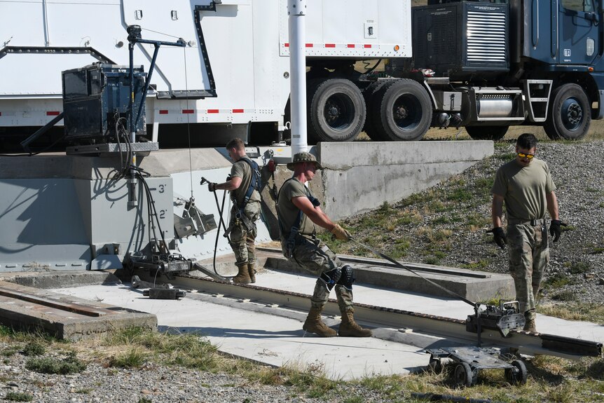 US airmen in uniform work to open a blast door covering a missile silo in Montana