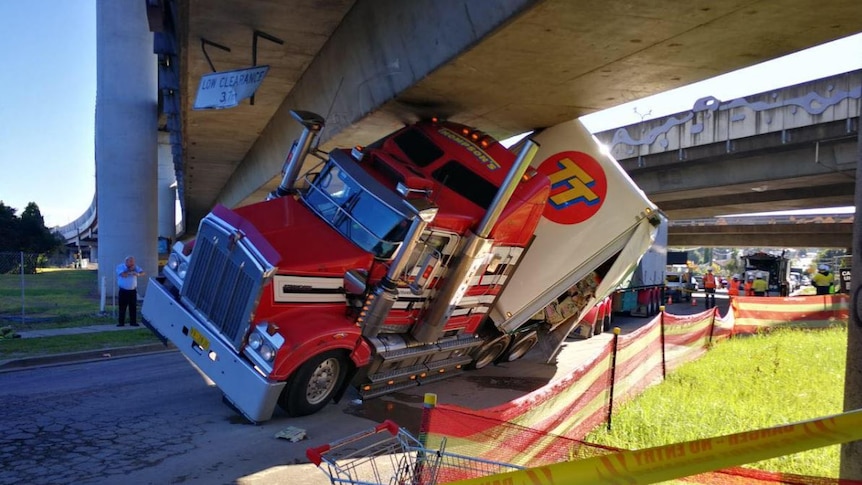 Large truck wedged under bridge.