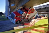 Large truck wedged under bridge.