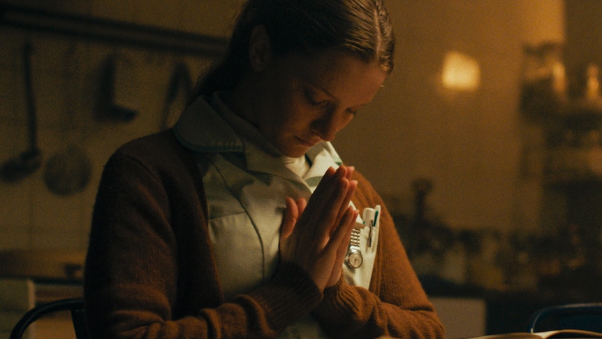 a woman praying in a kitchen, from the film Saint Maud.