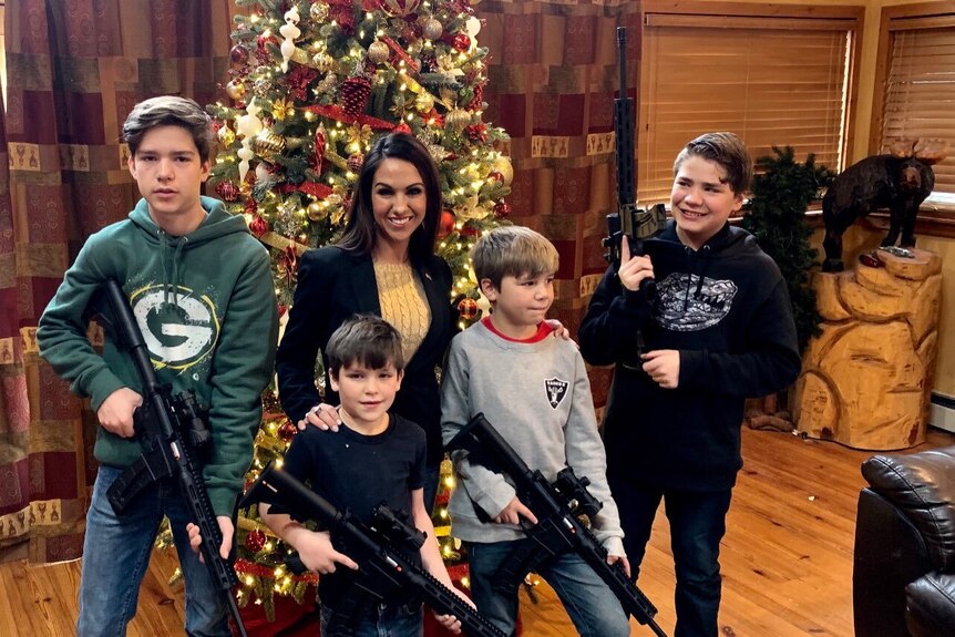 Une femme brune est assise parmi quatre garçons armés 