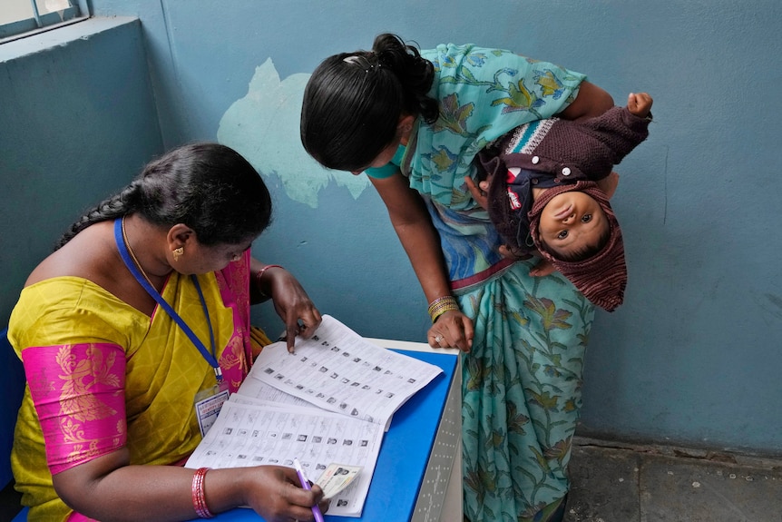 A woman checks for her name before casting her vote at a polling station in India.