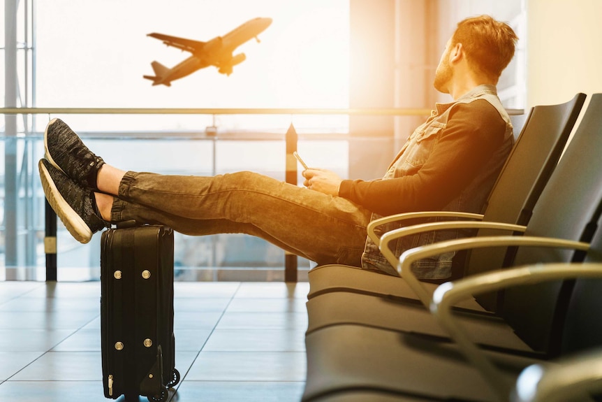 Man at airport watching plane take off