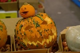 Two pumpkins carved out as jack-o'-lantern. They are both bright orange  the large one is on the bottom and small one ontop