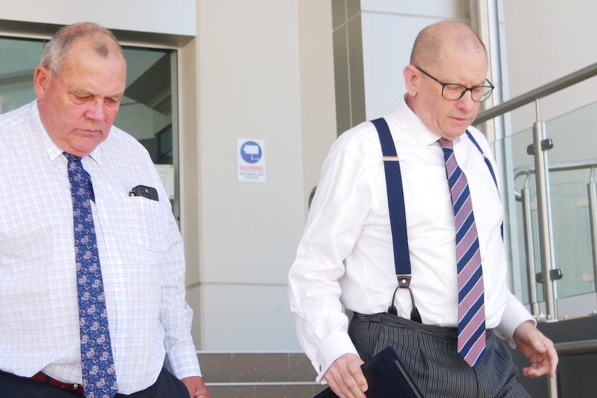 Two older men leave court, they are wearing business clothes one is wearing glasses
