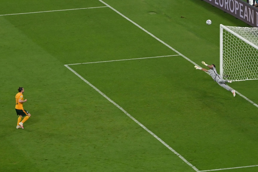 Welsh footballer Gareth Bale stands on teh penalty spot as his kick flies over the goalkeeper and the crossbar at Euro 2020.