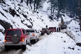 Vehicles are left stranded on a hillside after the road ahead is covered with snow