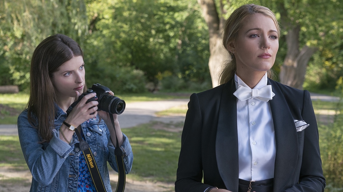 Colour still of Anna Kendrick holding camera and Blake Lively dressed in tux standing in park in 2018 film A Simple Favour.
