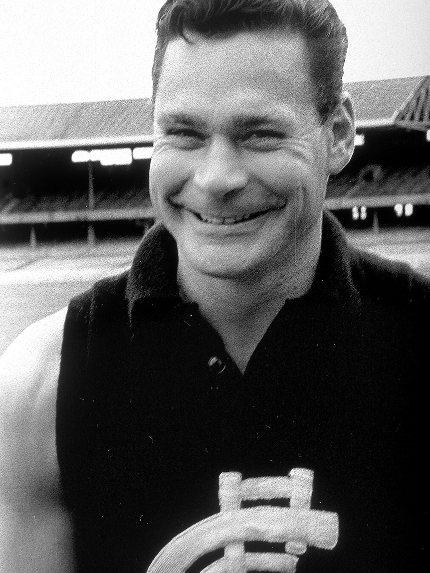 Ron Barassi smiles at a camera wearing a carlton jersey