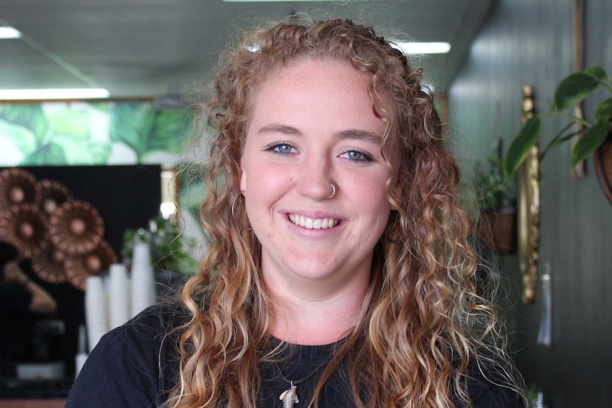 Hannah Aylward poses smiling in the middle of her cafe.